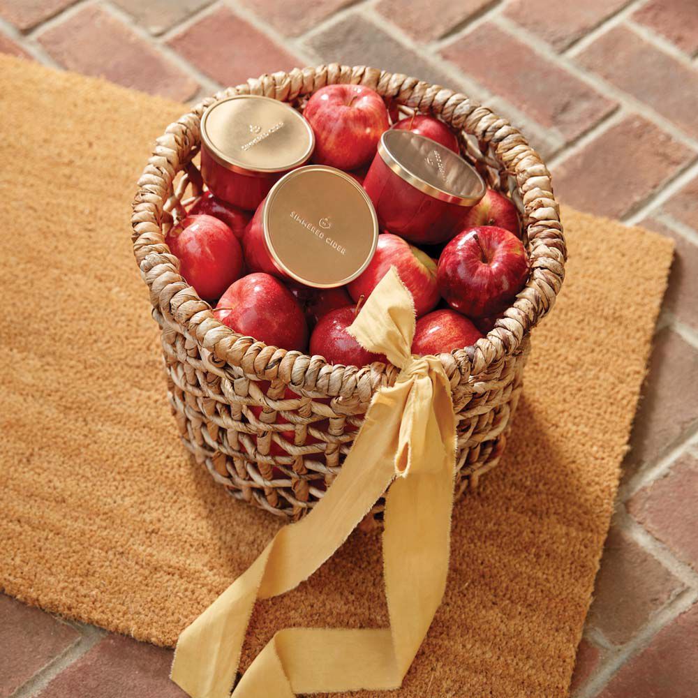 Thymes Simmered Cider Candle Tin with Gold Lid in basket on doormat image number 2